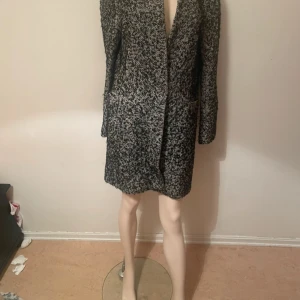 Svartvit kappa i grovstickad ullmix - Säljer en svartvit kappa i grovstickad ullmix med coolt mönster. Jackan har rak passform, djupa fickor och lång ärm. Perfekt för dig som gillar en stilren men ändå unik look.