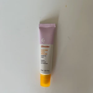 Glossier Lavender Balm Dotcom läppbalsam - Glossier Lavender Balm Dotcom är ett läppbalsam i en söt tub med lavendellila och vit design samt gul kork. Innehåller 15 ml och har en mild lavendeldoft. Perfekt för att ge läpparna extra fukt och glans. Smidig applikator och trendig look. Använd en gång. Säljs inte längre i denna förpackning och medel.