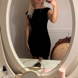 Svart tight kortklänning med öppen rygg - Säljer en svart tight kortklänning med snygg öppen rygg och breda axelband. Klänningen har en enkel, stilren design och sitter figurnära.