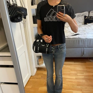 Svart Adidas t-shirt - Svart tränings t-shirt från Adidas med stor logga på framsidan . Ärmarna har grått mönster. Perfekt för träning. Står storlek (14-15) år/170 och passar XS/S. 