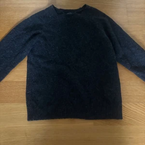 Mörkgrå stickad tröja från Vero Moda - Mysig mörkgrå stickad tröja från Vero Moda i enkel och klassisk modell. Tröjan har rund halsringning och långa ärmar, perfekt för kyliga dagar. Passar dig som gillar en stilren och avslappnad look.