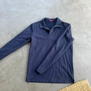 Mörkblå pikétröja från RYVLS - Säljer en riktigt snygg långarmad pike då jag växt ur den, köpt på kidsbrandstore och är i top skick! Hör av er vid frågor