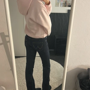 Wrangler mörkblå bootcut jeans - Mörkblå jeans från wrangler tydlig W-detalj på bakfickorna. Modellen har låg midja och bootcut-ben, säljer då de är lite för små och inte kommer till användning. Använda några fåtals gånger. 