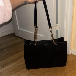 Svart axelväska DKNY - Svart axelväska från DKNY i skinn. Dustbag medföljer. Finns i Stockholm. 