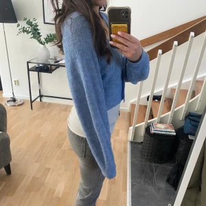 Ljusblå croppad kofta med stora knappar - Säljer en ljusblå croppad kofta med knappar framtill, Koftan är stickad, har v-ringning och långa ärmar. Perfekt för höst💕Superfin att styla över linne eller t-shirt💓bra skick och använd fåtal gånger!