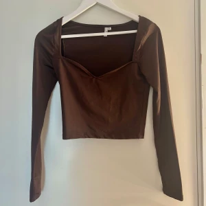 Brun långärmad croppad topp - Snygg brun långärmad topp med croppad passform och v-ringad hals. Aldrig använd.