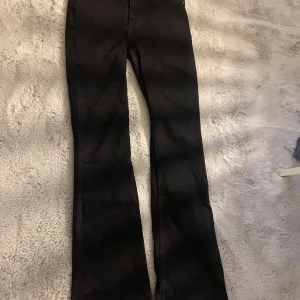 Svarta bootcut jeans från Gina Tricot - Snygga svarta jeans från Gina Tricot. Byxorna har bootcut-ben, klassisk femficksdesign.Jeansen är tillverkade i stretchig denim för en bekväm passform och har en stilren look som passar till allt.