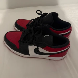 Nike Air Jordan 1 Low ”Bred Toe” - Storlek 47, Värde på cirka 2000-2500kr nypris. Har inte kvar boxen. Använda cirka 4-5 gånger. Nike Air Jordan 1 Low i klassisk färgkombination av rött, svart och vitt. Skorna har svart snörning, vit mellansula.