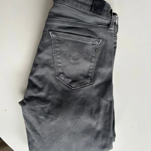 Replay grå skinny jeans New Luz - Snygga grå jeans från Replay, modell New Luz. De har en tight passform med klassiska fem fickor och dragkedja. Jeansen är i stretchigt material som sitter skönt och följer kroppen. Perfekta för dig som gillar en stilren och modern look.