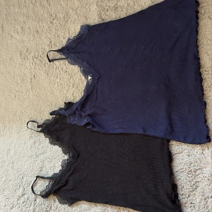 2 spetslinnen från Amisu, svart & marinblå - Säljer två snygga linnen från Amisu i storlek S och XS. Ett är svart och det andra är marinblått, båda med tunna axelband och v-ringning med spetskant. Materialet är mjukt och stretchigt, perfekt för lager-på-lager eller som statement-piece. Säljes tillsammans!