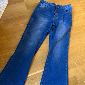 Blå bootcut jeans från Evigh - Snygga blå jeans från Evigh med klassisk femficksmodell och bootcut-ben. Jeansen har hög midja och är tillverkade i mjukt denimtyg med lätt tvättad look. Perfekta för dig som gillar en avslappnad men trendig stil.
