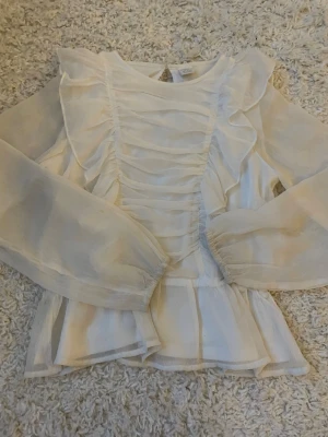 Vit volangblus med puffärmar🪽💌 - Säljer en superfin vit blus med volangdetaljer och puffiga ärmar. Blusen har rynkade partier framtill och är gjord i ett tunt, skirt material🥨🪽