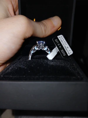 Silverring med blå sten och detaljer - Snygg silverfärgad ring med en stor blå sten i mitten och mindre klara stenar på sidorna. Ringen har en elegant och unik design som verkligen sticker ut. Perfekt accessoar för att lyfta din stil.