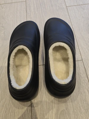Svarta tofflor med fuskpälsfoder - Svarta, varma och bekväma skor för arbete i kök/restaurang. Helt nya, aldrig använda.