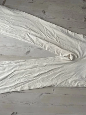 Vita leggings från Lululemon XS - Säljer ett par vita leggings från Lululemon i storlek XS. De är mjuka och stretchiga, perfekta för dig som vill ha bekväma och stilrena tights. Materialet är en blandning av nylon och elastan som ger en fri passform och bra rörelsefrihet.