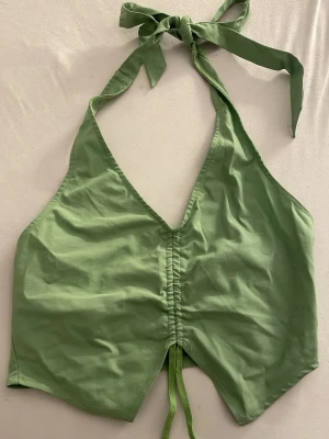 Vacker Grön halterneck topp från H&M  - Helt NY Snygg ljusgrön halterneck topp från H&M Divided med knyt i nacken och framtill. Perfekt för semester och varma dagar. Med en croppad passform och är tillverkad i mjuk bomull. Perfekt för varma dagar och enkel att styla med jeans eller kjol.