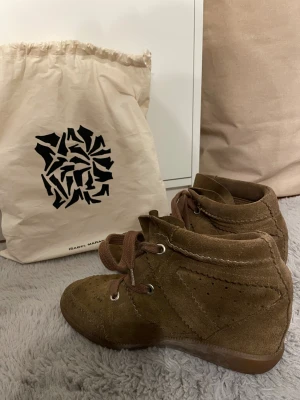  Isabel Marant Bobby sneakers  - Bruna sneakers från Isabel Marant i mjuk mocka med snörning och diskreta perforerade detaljer. Skorna har en platt gummisula och rund tå, samt en klassisk Isabel Marant-påse medföljer. Perfekta för dig som gillar en avslappnad men trendig stil🤗