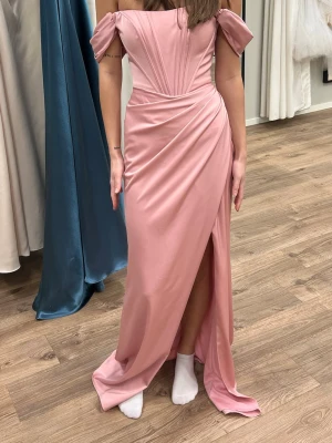 Balklänning - Elegant rosa balklänning med offshoulder-ärmar, snörning i ryggen och markerad midja. Klänningen har en hög slits framtill och draperade detaljer. Perfekt till balen! helt ny och oanvänd med prislapp kvar 🥰köpt på nordic wedding