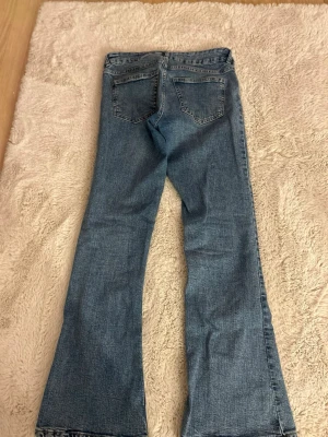 Blå bootcut jeans  - Ett par klassiska blå bootcut jeans. Jeansen har fyra fickor och normal passform i midjan. Jag säljer dem eftersom att dem har blivit för korta för mig jag är ungefär 1,74 cm lång.