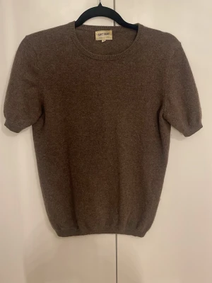  kashmirtröja Soft Goat - Mjuk och stilren brun stickad tröja från Soft Goat i 100% kashmir. Tröjan har korta ärmar, rund halsringning och ribbade kanter. Perfekt för dig som gillar en enkel men lyxig look. Använt 2-3 gånger men är så gott som ny, inga noppror eller trådar. Nytt pris 1995:-