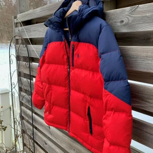 Ralph Lauren Röd Dunjacka - Säljer denna snygga Vinterjacka Från Ralph Lauren. Storlek L i barnstorlek vilket uppskattas till en XS i vuxenstorlek. Fint skick utan defekter, lite smuts på huvan bara men går bort i tvätt. använd ungefär en månad. Tyckte det var svårt att fånga rätt färg på jackan så se bild 4 för hur färgen ser ut i verkligheten. Nypris 3300.