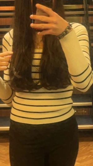 Vit ribbad randig långärmad tröja - Snygg vit ribbad tröja med svarta ränder och lång ärm. Materialet är stickat och känns mjukt mot huden. Säljs pga ingen användning 