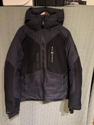 Sail Racing Pole Down Vectran Jacket Carbon Limited Edition - Sail Racing jacka i modellen ”Pole Down Vectran Jacket” i färgen Carbon Limited Edition. Slutsåld överallt. Jackan är vatten och vindtät, och  håller dig varm i alla väder. Köptes förra vintern för nypris 10.000kr, endast använd den vintern. Små skavanker finns: en innerficka går ej att stänga(bild 4), litet rivmärke på ena ärmen(bild 5 ), texten på luvan blivit lite sliten (bild 2) Överlag superfint skick. Oringalförpackning, prislappar, följesedel kvar. Pris kan diskuteras, och mått kan fås. 