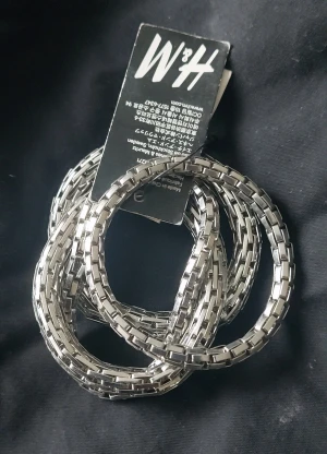 Silverfärgade armband från H&M - Säljer ett set med flera chunky armband från H&M i silverfärg. Armbanden har en cool kedjeliknande design som ger en edgy vibe och passar perfekt för att lyfta din outfit. Metallisk look och stilren form gör dem till ett statement på handleden.