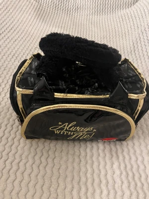 Svart konståkningsväska från Edea - Svart konståkningsväska från Edea. Väskan är  glansig och har guldiga detaljer, hndtaget är fluffigt och mjukt.