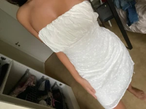 Vit axelbandslös kort klänning - Supersöt vit axelbandslös klänning med lätt rynkad överdel och broderade blommor på kjolen. Kort modell som sitter tajt och framhäver figuren. Perfekt för dig som vill ha en fräsch och somrig look.