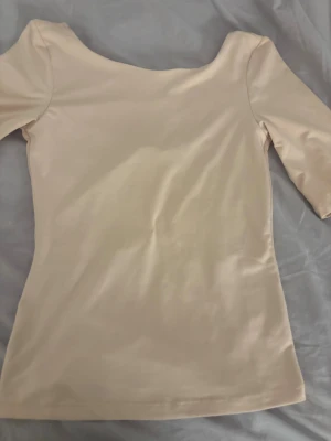 Ljusrosa tröja från hm - Säljer en stilren rosa tröjan med mjuk glans och djup rundad urringning där bak. Tröjan har trekvartsärm och är figurnära i modellen, perfekt för dig som gillar minimalistisk och elegant stil. Passar dig som vill ha en enkel men snygg topp.