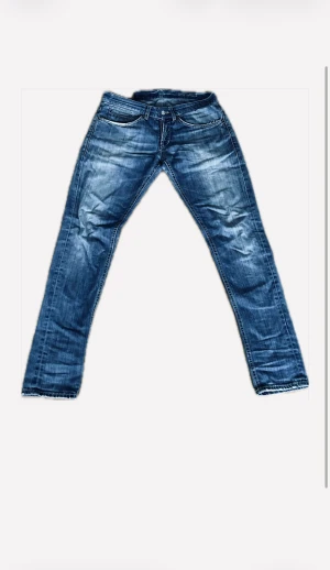 Dondup jeans - Snygga blå Dondup jeans med slitna detaljer, fem fickor och coola sömmar på bakfickorna med metall-D. Materialet är robust denim i bomull och färgen är mellanblå med tvättade effekter.