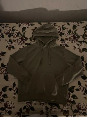 Grå hoodie från Define med huva - Snygg grå hoodie från Define med broderad logga på bröstet. Tröjan har en stor huva med snörning och en klassisk magficka. Mjuk bomullskänsla och långärmad modell, perfekt för chill dagar eller när du vill vara extra comfy.