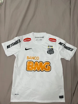 Santos Neymar Jr matchtröja Nike S - Säljer en vit Santos FC fotbollströja från Nike med Neymar Jr och nummer 11 på ryggen. Tröjan har korta ärmar, Dri-Fit material och flera sponsorer som BMG, Netshoes och Seara. Klubbmärket är broderat på bröstet och tryck i svart och orange. Använd 1 gång.