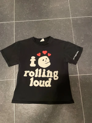 Rolling Loud t-shirt Broken Planet S - Svart t-shirt från Broken Planet med Rolling Loud-tryck fram och bak, samt namn på artister som Travis Scott, Playboi Carti och Meek Mill. Färgglada grafiska motiv och texten 'portugal 2023' på ärmen. Klassisk passform och rund hals.