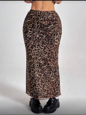 Leopardmönstrad långkjol från SHEIN - Säljer en snygg långkjol från SHEIN med leopardmönster i bruna och svarta toner. Kjolen har en figurnära passform och är tillverkad i ett lätt och mjukt syntetmaterial. Perfekt för dig som vill sticka ut med en trendig look.