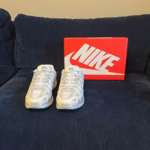 Nike P-6000 vita sneakers - Nike P-6000 sneakers i en fräsch vit och ljusgrå färg med mesh och syntetpaneler. Skorna har snörning, rund tå och en platt sula med tydlig struktur. Snygg retrostil med diskreta detaljer och klassisk Nike-logga på sidan och tungan.