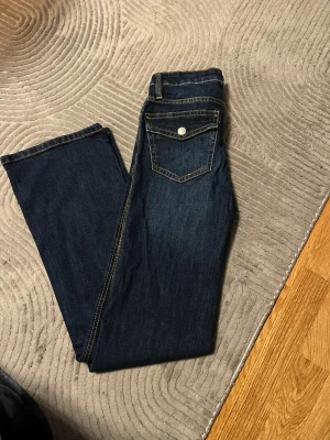 Mörkblå bootcut jeans från 157 - Snygga mörkblå jeans med bootcut passform från 157. Klassisk femficksdesign med silverfärgade knappar på bakfickorna och kontrastsömmar. Jeansen har normal midja och är tillverkade i slitstarkt denimtyg som ger en cool look.