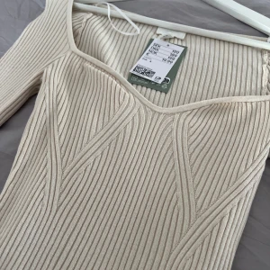 Beige ribbad tröja - Beige ribbad tröja med långärmad design och en v-ringad hals. Helt oanvänd. 
