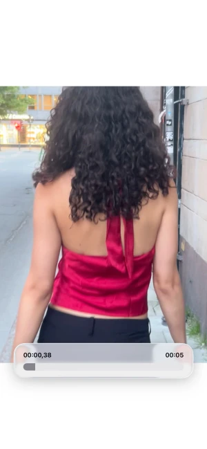 Röd omlott linnetopp i satin - Säljer en röd omlott linnetopp i glansigt satinmaterial. Toppen är croppad och har en snygg öppen rygg med knyt i nacken. Perfekt för dig som gillar att sticka ut med färg och vill ha en trendig look. Passformen är loose och toppen är ärmlös.