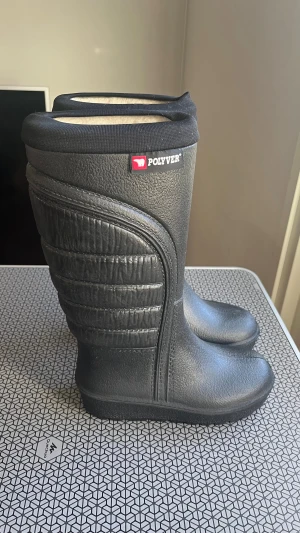 Svarta vinterstövlar från Polyver (powerboots) st 35-36 - Svarta vinterstövlar från Polyver med högt skaft och quiltad detalj på sidorna. Tillverkade i syntetmaterial med mjuk, varm insida. Perfekta för kalla dagar och snö, med platt sula och rund tå för extra komfort.
