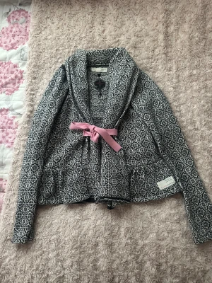 Mönstrad cardigan jacka Odd Molly ( pris diskuteras) - Supersnygg svartvit cardigan jacka från Odd Molly med grafiskt mönster och rosa knytband i midjan. Jackan har lång ärm, bred krage och broderad detalj på insidan. Perfekt för dig som gillar unika detaljer och skön passform.Använd en gång så i topp skick.