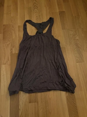 Mörkgrå linnetopp från 7 for all mankind - Säljer en mörkgrå linnetopp från 7 for all mankind i storlek M. Toppen har en loose passform, ärmlös design och snygg knytning i ryggen. Materialet är mjukt och tunt, perfekt för varma dagar. Stilren och enkel att matcha med dina favoritjeans eller shorts. Sitter löst o fint, vintage få den är från runt 2000! Inga defekter 