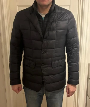 Herno jacka - Superfin trendig och eftertraktad blå varm Herno dunjacka med insydd väst. Storlek 50 (M). En enda defekt invändigt och det är att Herno loggan invändigt är trasig vilket ej syns vid användning. Inga hål eller fläckar och sjukt snygg jacka som passar till allt.