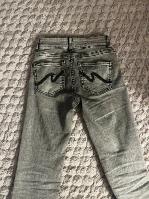 Bootcut jeans i grå tvätt från Nelly - Bootcut jeans från Nelly i grå tvätt med låg midja och snygga svarta sömmar på bakfickorna. Storlek 34 och inga defekter!!