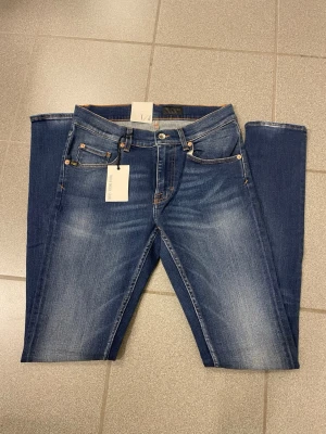 Blå Tiger of Sweden W30 - Snygga blå jeansbyxor från Tiger of Sweden  i tight fit med smal fot. Klassisk femficksdesign, kontrastsömmar och läderpatch bak i midjan. Jeansen har en lätt tvättad look och passar dig som gillar smalare siluett.