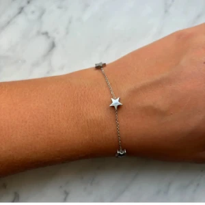 Silverarmband med stjärnor - Sälj detta eleganta silverarmband med stjärnor på från Edblad. Armbandet har en justerbar kedja och ett smidigt klolås för enkel användning. Perfekt för att lägga till en subtil glans till din outfit. Finns en liten defekt på armbandet (bild 2) men det har absolut ingen alls påverkan på självaste armbandet och syns ej när man har på det! Säljer för att jag ej längre bär silversmycken!! Ny pris 349kr. Pris kan diskuteras vid snabb affär!!😊