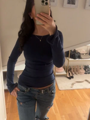 Mörkblå offshoulder långärmad topp - Säljer en mörkblå långärmad topp med slim passform. Toppen har en enkel och stilren design med rund halsringning och är tillverkad i ett mjukt, stretchigt material som sitter snyggt på kroppen. Perfekt att matcha med jeans eller kjol.
