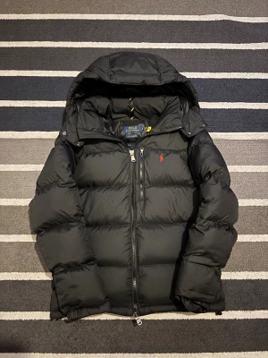 Polo Ralph Lauren Jacka - Svart - Tjena! Säljer nu denna Ralph Lauren jackan, jättefint skick på den. Skick 10/10, använd runt 8 gånger alltså inga skador eller hål. Säljs då jag har köpt en annan jacka. Storlek S, passar ifrån 170- 180 beroende på vikt. Vid frågor kontakta gärna! Priset går att diskuteras lite.