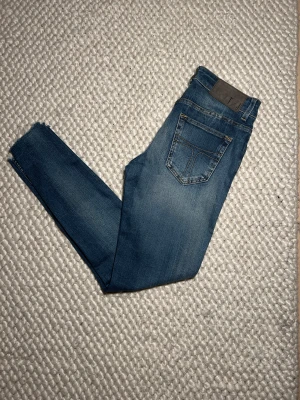 Tiger of Sweden blå skinny jeans - Snygga blå jeans från Tiger of Sweden med skinny passform och klassisk femficksdesign. Jeansen har ljus tvätt, gul kontrastsöm och rå kant vid benslut. Tillverkade i bomull och polyester för skön stretch. Perfekta för dig som gillar smal siluett.